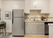 Thumbnail 3 of 13 - A kitchen with a refrigerator, sink, and cabinets.