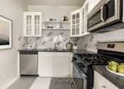 Thumbnail 2 of 25 - A modern kitchen with white cabinets and black appliances.