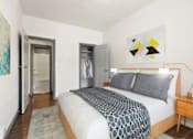 Thumbnail 9 of 25 - A bedroom with a bed, nightstand, and a painting on the wall.