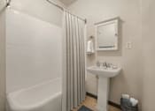 Thumbnail 11 of 25 - A white bathroom with a white sink and a white bathtub.