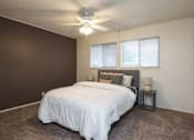 Thumbnail 1 of 9 - A bedroom with a bed, pillows, a nightstand, and a ceiling fan.
