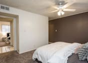 Thumbnail 4 of 9 - A bedroom with a bed, ceiling fan, and a doorway leading to another room.