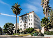 Thumbnail 11 of 13 - A white building with a balcony is surrounded by palm trees.