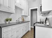 Thumbnail 3 of 13 - A kitchen with white cabinets and a black stove top.
