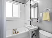 Thumbnail 8 of 13 - A white sink is in a bathroom with a white tub and a white toilet.