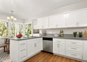 Thumbnail 16 of 27 - A kitchen with white cabinets and a wooden floor.