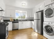Thumbnail 11 of 27 - A modern kitchen with a washing machine and dryer built into the cabinetry.