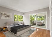 Thumbnail 19 of 27 - A bedroom with a large bed and a view of a balcony with a couch and plants.