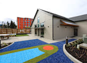 Thumbnail 12 of 36 - a playground with a blue carpet in front of a building