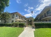 Thumbnail 1 of 7 - an apartment building with a lawn and a sidewalk
