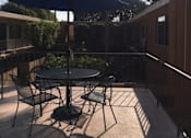 Thumbnail 21 of 21 - A patio with a table and chairs under an umbrella.