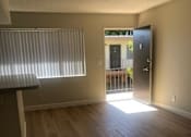 Thumbnail 1 of 21 - A room with wooden floors and a door leading outside.