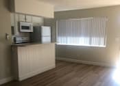 Thumbnail 2 of 21 - A kitchen with wood flooring and a window with blinds.