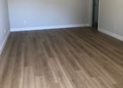 Thumbnail 3 of 21 - A room with a light brown wooden floor and a white wall with a window.
