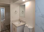 Thumbnail 21 of 22 - A white toilet with a sink and mirror in a bathroom.