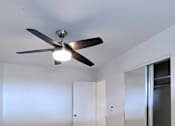 Thumbnail 18 of 22 - A room with a ceiling fan and light fixture, hardwood floors, and white walls with a door on the right.