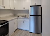 Thumbnail 17 of 22 - A kitchen with white cabinets and a stainless steel refrigerator.