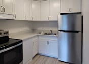 Thumbnail 16 of 22 - A kitchen with white cabinets and a stainless steel refrigerator.