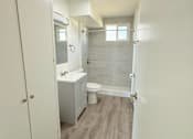 Thumbnail 15 of 18 - A small bathroom with a toilet, sink, and shower.