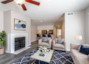 Thumbnail 4 of 47 - A living room with a fireplace, a ceiling fan, and a painting on the wall.