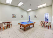 Thumbnail 17 of 19 - A pool table is surrounded by four chairs in a room with white walls.