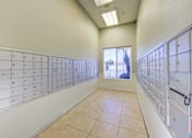 Thumbnail 16 of 19 - A room with a long row of mailboxes on both sides and a window in the middle.