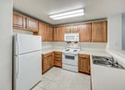 Thumbnail 5 of 19 - A kitchen with wooden cabinets and white appliances.