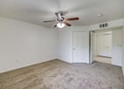 Thumbnail 7 of 19 - A room with a ceiling fan and carpeted floor.