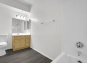 Thumbnail 36 of 48 - A white bathroom with a wooden vanity and a white toilet.