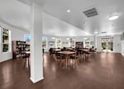Thumbnail 11 of 48 - A room with wooden floors and tables surrounded by bookshelves.