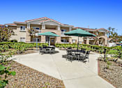 Thumbnail 6 of 48 - A patio with a table and chairs is in front of a building.