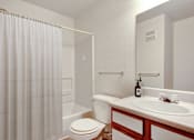 Thumbnail 23 of 33 - A white bathroom with a toilet, sink, and shower curtain.