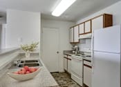 Thumbnail 24 of 33 - A kitchen with a bowl of apples on the counter.