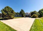 Thumbnail 9 of 33 - A basketball hoop is visible in the background of a grassy area with a concrete pathway leading to a basketball court.