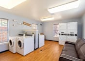 Thumbnail 15 of 33 - A laundry room with a couch and washing machines.