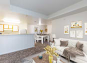 Thumbnail 22 of 33 - A living room with a white couch and a yellow vase on the coffee table.