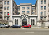 Thumbnail 1 of 15 - a large building with cars parked in front of it on a city street