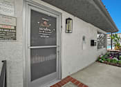 Thumbnail 71 of 73 - A building entrance with a glass door and a sign on the wall.