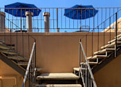 Thumbnail 16 of 21 - A staircase with a metal railing and a blue umbrella above it.