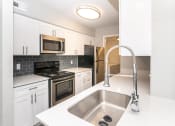 Thumbnail 2 of 35 - a kitchen with white cabinets and black appliances and a sink
