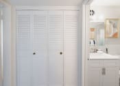 Thumbnail 15 of 24 - a bathroom with white cabinets and a large closet with shutters