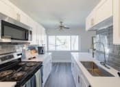 Thumbnail 2 of 24 - a kitchen with white cabinets and black appliances and a sink