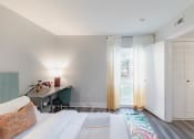 Thumbnail 17 of 24 - a bedroom with a bed and a desk and sliding glass doors