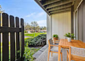 Thumbnail 21 of 27 - A wooden table and chairs are on a patio with a view of a backyard.