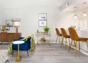 Thumbnail 7 of 35 - a living area with a blue chair and a kitchen with a bar table and chairs