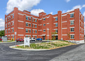 Thumbnail 1 of 20 - Mount Joy Senior Housing | a large red building with a parking lot in front of it