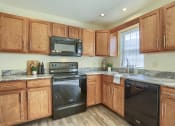 Thumbnail 41 of 51 - Mechanicsburg Apartments | Rockledge Townhomes |  a kitchen with wood cabinets and black appliances