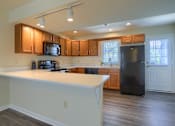 Thumbnail 39 of 58 - A kitchen with a black refrigerator and wooden cabinets.