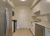Thumbnail 10 of 39 - A kitchen with a stainless steel refrigerator and white cabinets.