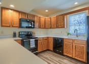 Thumbnail 40 of 58 - A kitchen with wooden cabinets and black appliances.